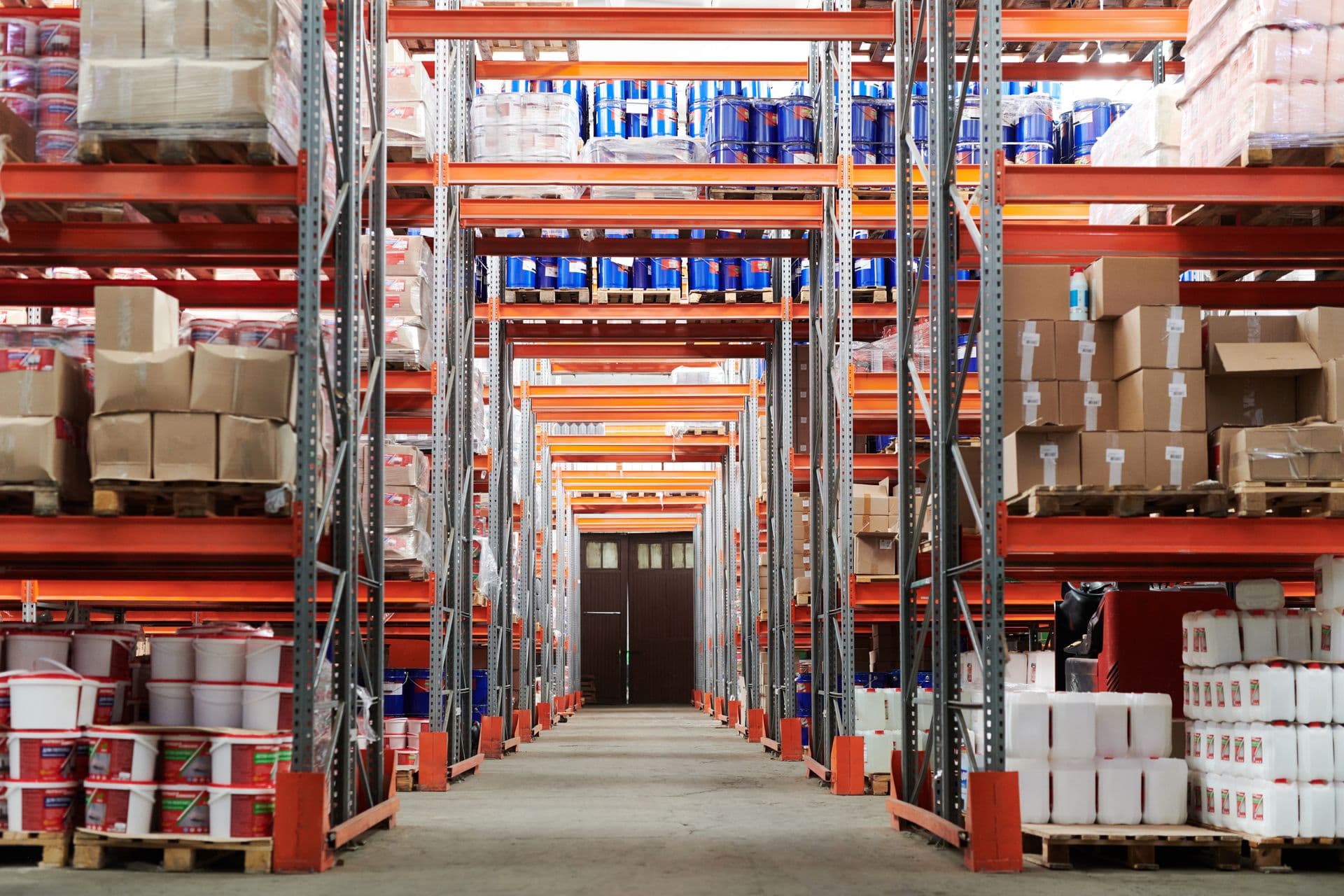 Warehouse aisle with pallet racking, boxed inventory, and receiving dock doors